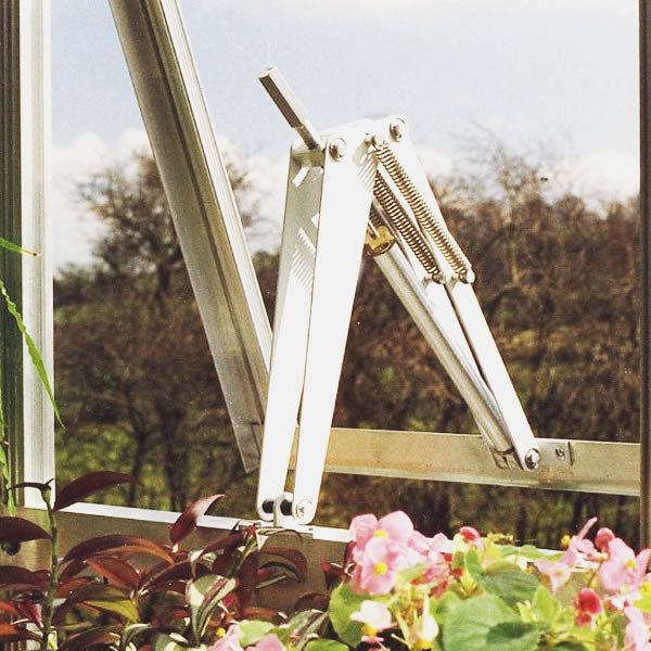 Bayliss Triple Spring Solar Vent Opener shown operating in a greenhouse filled with flowers.