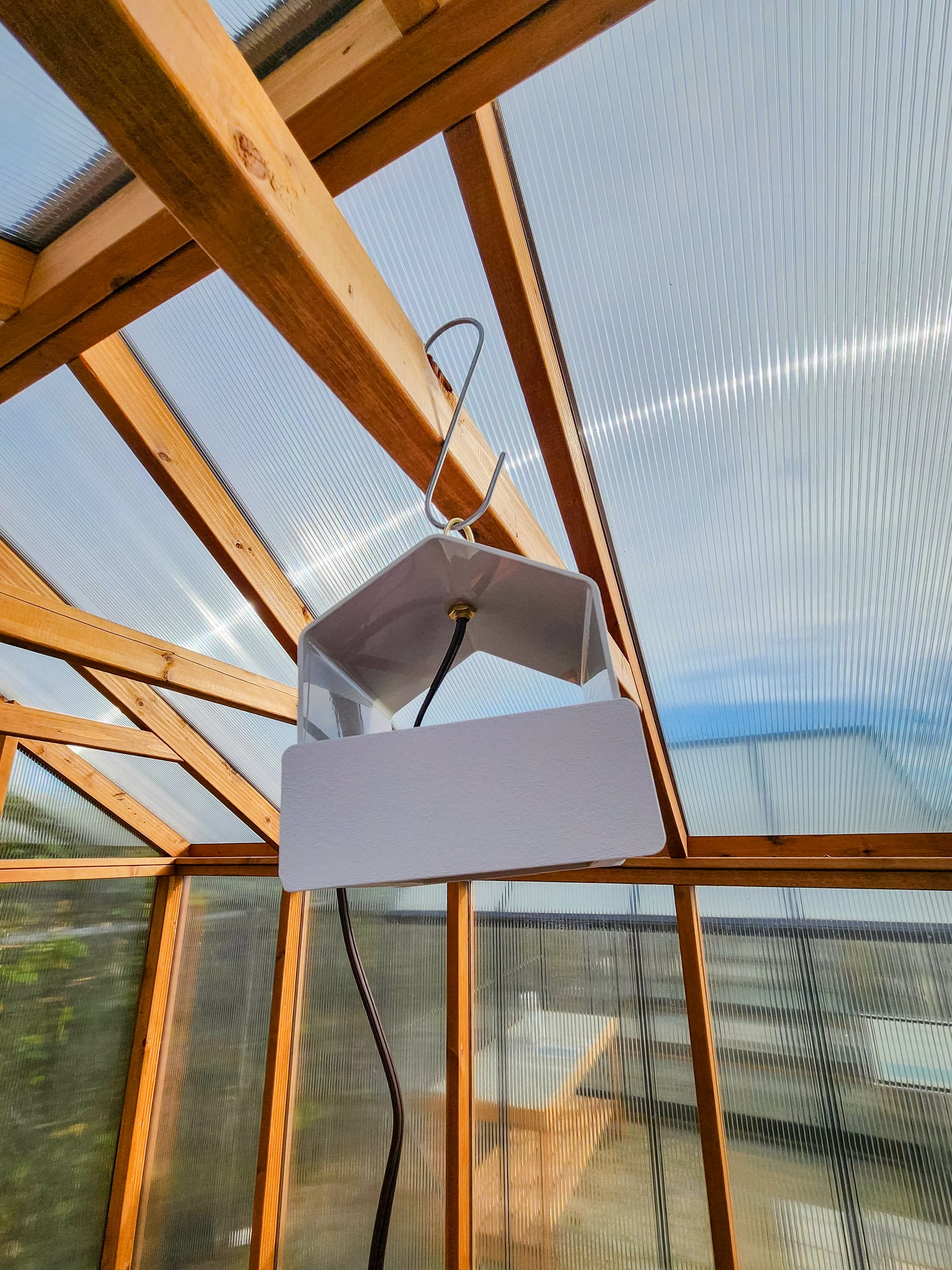 Heat Saver Fan: A side view of the product hanging in a greenhouse.